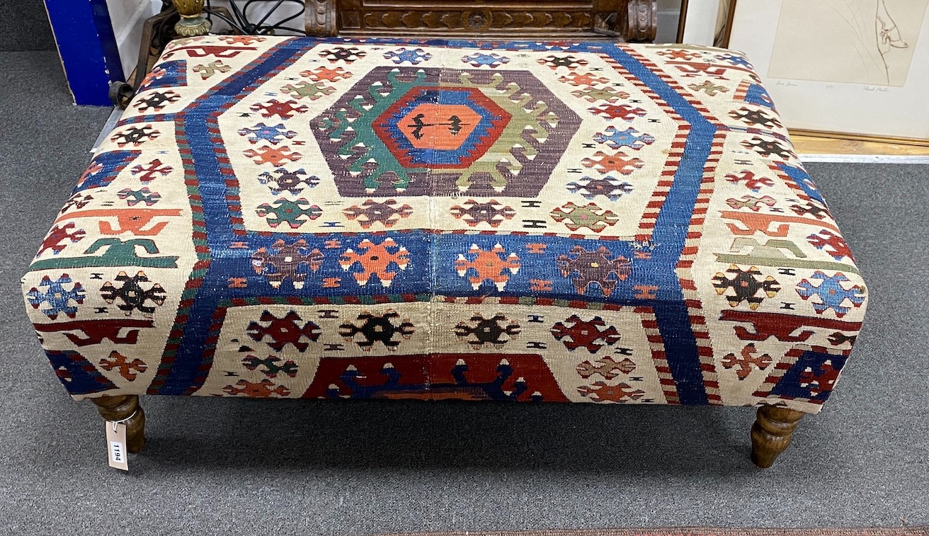A large rectangular coffee table / footstool with antique kelim upholstery on stained turned beech feet, width 107cms, depth 72cms, height 37cms.